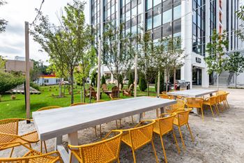 an outdoor patio with tables and chairs and a building in the background